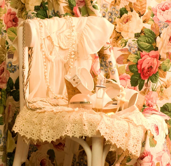 Винтажное элегантное платье и парфюмерные бутылки на белом стуле — стоковое фото