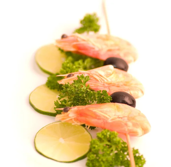 Broche à crevettes avec citron vert et olives sur fond blanc — Photo