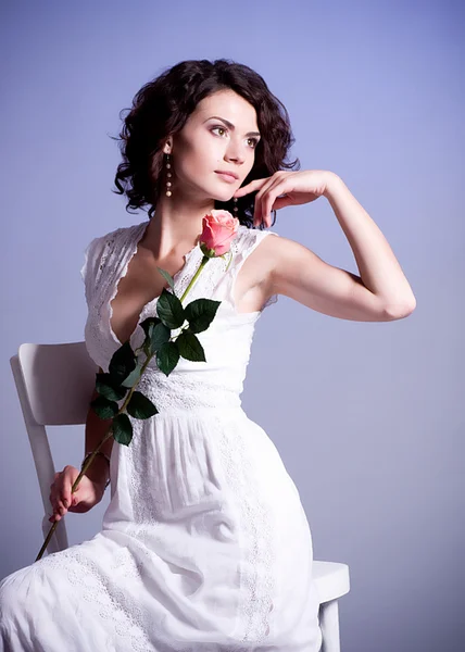 Jonge vrouw in bruids jurk met roos op achtergrond. — Stockfoto