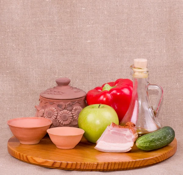 Clay pots, apple, vegetables, oil and meat pork — Stock Photo, Image