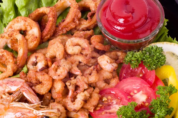 Вкусные жареные кольца кальмара и жареные креветки с овощами — стоковое фото
