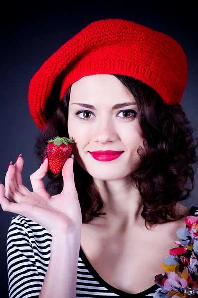 Junge Frau mit Erdbeere in roter Baskenmütze — Stockfoto