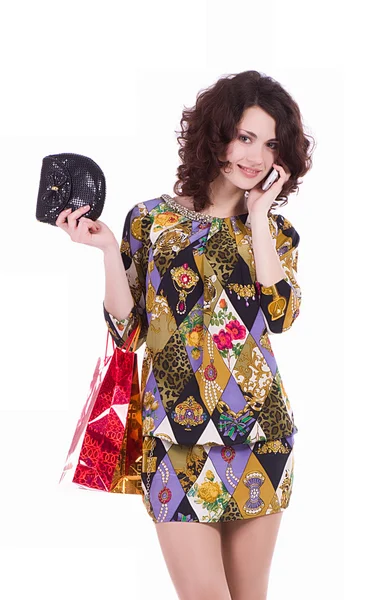 Mujer joven con bolsas de compras hablando en el teléfono celular sobre un fondo blanco —  Fotos de Stock