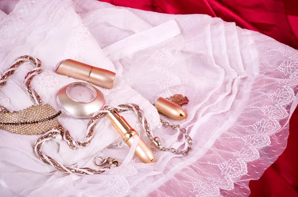 Golden jewelry and white lace on red background — Stock Photo, Image