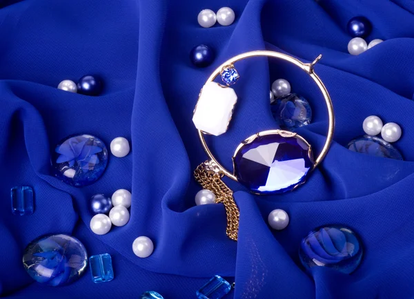 Zlaté šperky na modrém pozadí — Stock fotografie