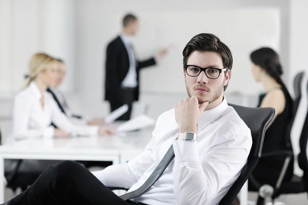 Knappe jonge zakenman met collega's op achtergrond — Stockfoto