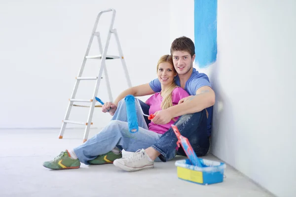 Heureux jeunes gens se détendre après avoir peint dans une nouvelle maison — Photo