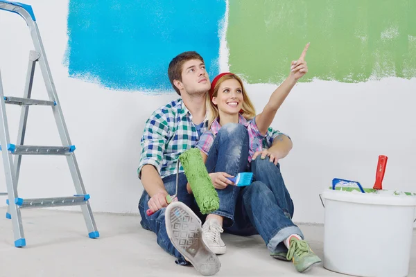 Счастливая пара покрасит стену в новом доме — стоковое фото