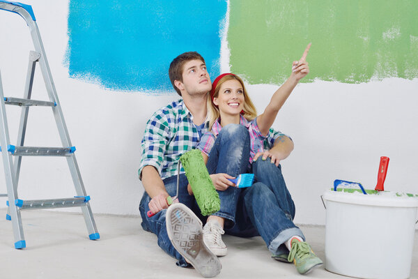 Happy couple paint wall at new home