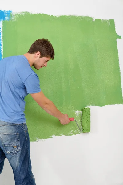Красивий молодий чоловік малює білу стіну в кольорі — стокове фото