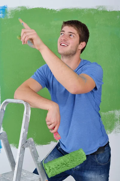 Pohledný mladý muž malujte bílou stěnu v barvě — Stock fotografie