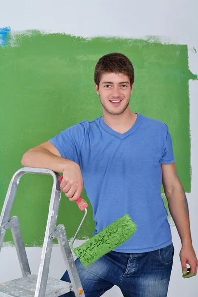 Красивый молодой человек красить белую стену в цвет — стоковое фото