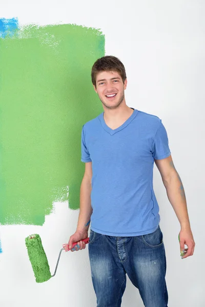 Красивый молодой человек красить белую стену в цвет — стоковое фото