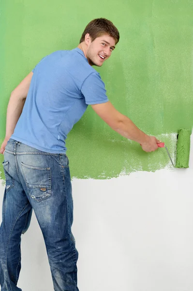 Guapo joven pintar pared blanca en color —  Fotos de Stock