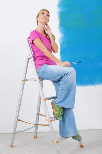 Счастливая улыбающаяся женщина рисует интерьер дома — стоковое фото
