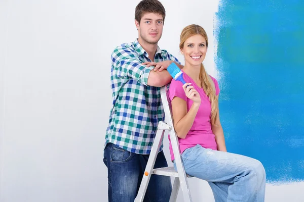 Щаслива пара фарбує стіну в новому будинку — стокове фото