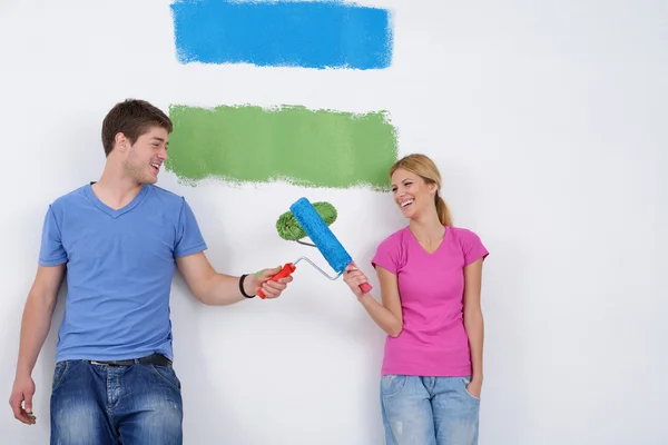 Счастливая пара покрасит стену в новом доме Стоковая Картинка