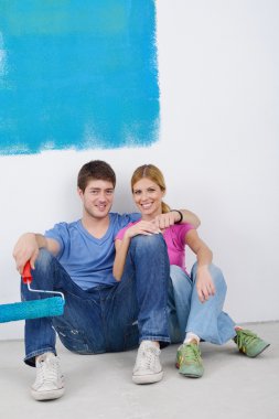 Happy young cople relaxing after painting in new home clipart