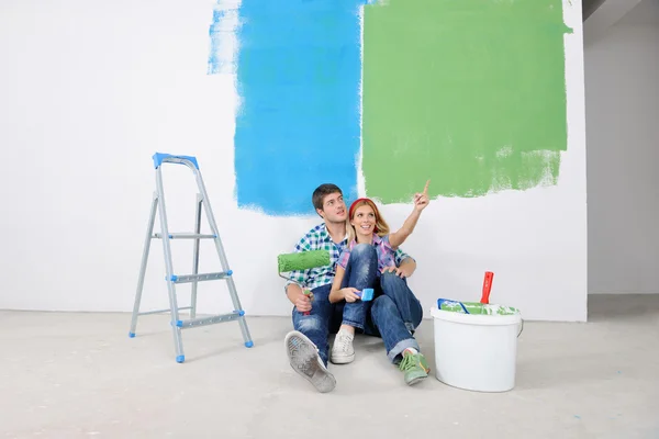 Счастливые молодые люди расслабляются после рисования в новом доме — стоковое фото