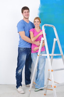 Mutlu çift yeni evinde duvarları boyuyor.