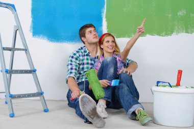Mutlu çift yeni evinde duvarları boyuyor.