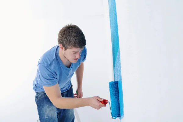 Handsome young man paint white wall in color — Stock Photo, Image