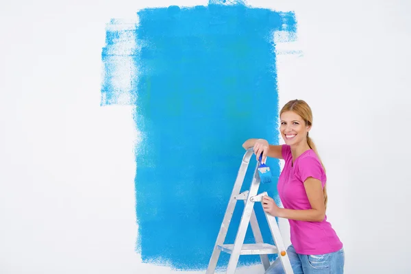 Glada leende kvinna måla insidan av hus — Stockfoto