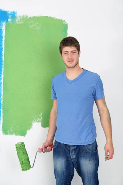 Schöner junger Mann bemalt weiße Wand in Farbe — Stockfoto