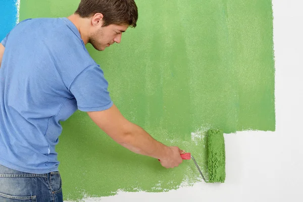 Schöner junger Mann bemalt weiße Wand in Farbe — Stockfoto