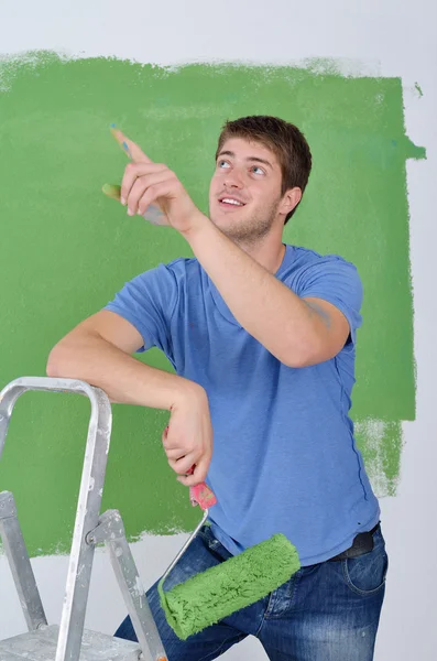 Bonito jovem pintar parede branca na cor — Fotografia de Stock
