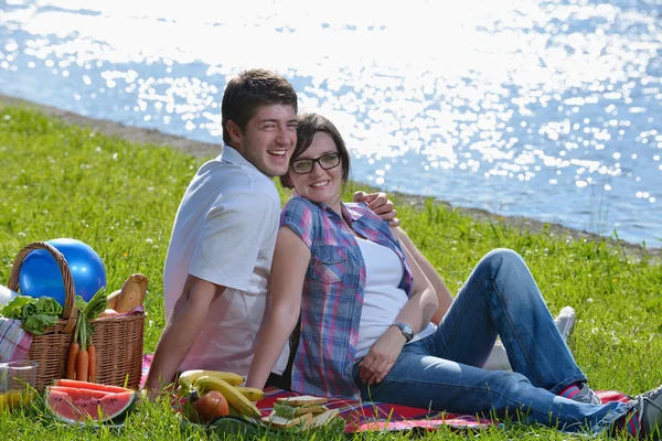 Heureux jeune couple ayant un pique-nique en plein air — Photo