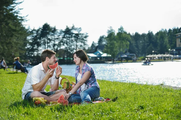 Heureux jeune couple ayant un pique-nique en plein air — Photo