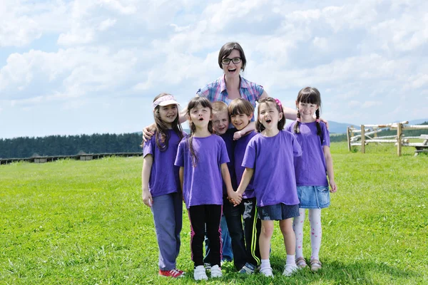 Fröhliche Kindergruppe mit Lehrer in der Natur — Stockfoto