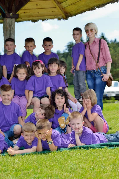 Grupo de crianças felizes com professor na natureza — Fotografia de Stock