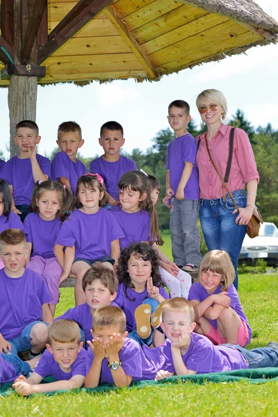 Felice gruppo di bambini con insegnante in natura — Foto Stock