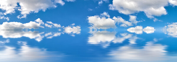 Blue sky with large white clouds and reflection