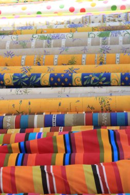 Rolls of Provencal textile on a market stall clipart