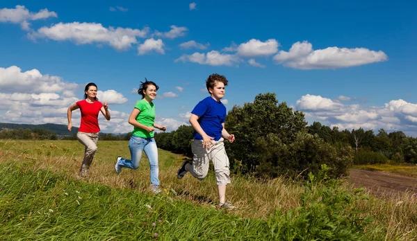 Active family - mother and kids running, jumping outdoor — Stock Photo, Image