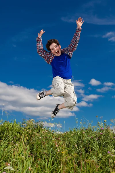 Chlapec na lyžích, běh proti modré obloze — Stock fotografie