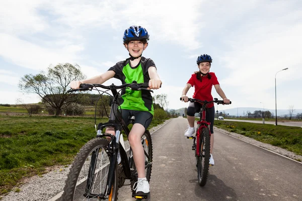 Девушка и мальчик катаются на велосипеде по дорожке — стоковое фото