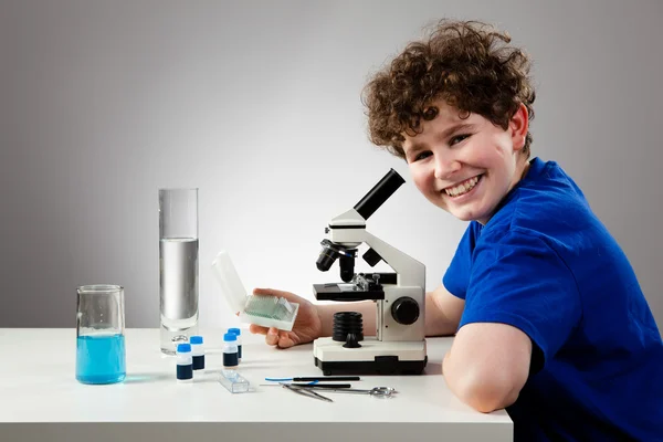 Мальчик осматривает препарат под микроскопом — стоковое фото
