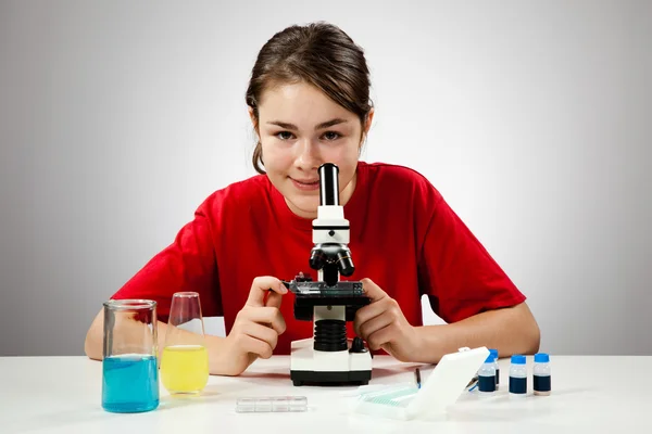 Menina examinando preparação ao microscópio — Fotografia de Stock
