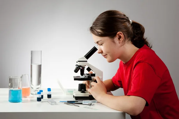 Chica examinando la preparación bajo el microscopio — Foto de Stock