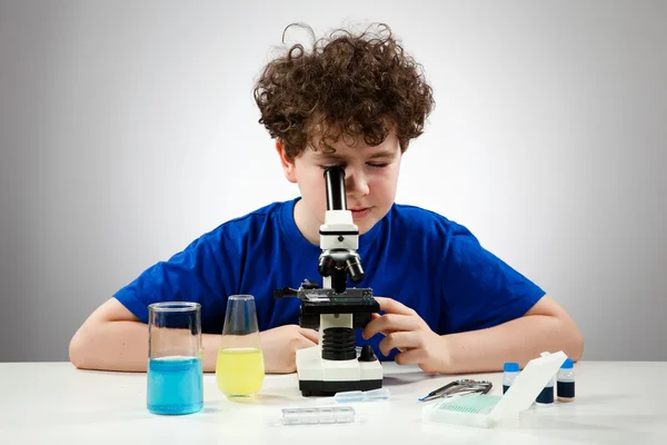 少年は、顕微鏡下で準備を調べる — ストック写真