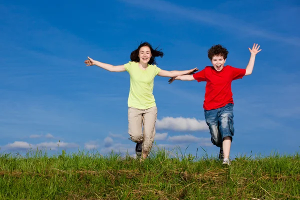 Menina e menino correndo, pulando ao ar livre — Fotografia de Stock