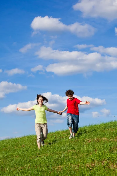 Dziewczyna i chłopak, bieganie, skakanie na zewnątrz — Zdjęcie stockowe