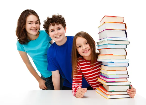Estudantes espreitando atrás de pilha de livros sobre fundo branco — Fotografia de Stock