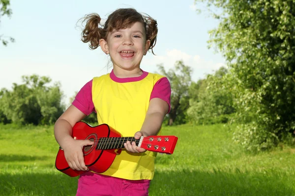 Fröhliches kleines Mädchen spielt Gitarre und singt — Stockfoto