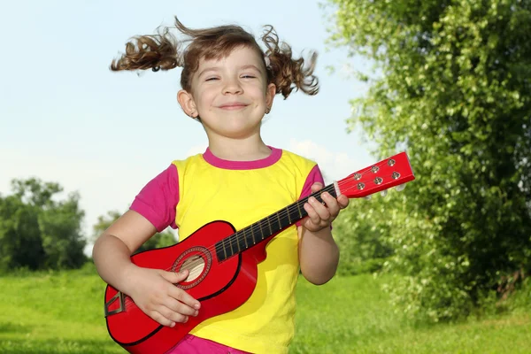 Счастливый маленький играть на гитаре под открытым небом — стоковое фото
