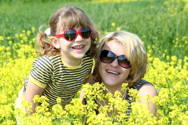Happy mother and daughter in yellow flowers field — Stock Photo, Image